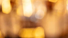 Man hiding red rose behind his back and gift for his smiling girlfriend while sitting in restaurant.